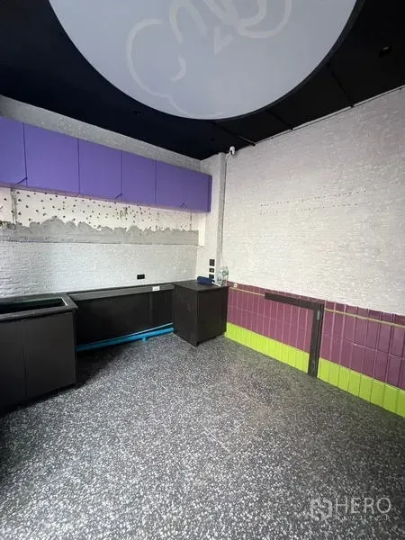 Retail Space for rent in Watthana, Bangkok - Retail workspace showing built-in counters, purple overhead cabinets, utility points, and speckled flooring.
