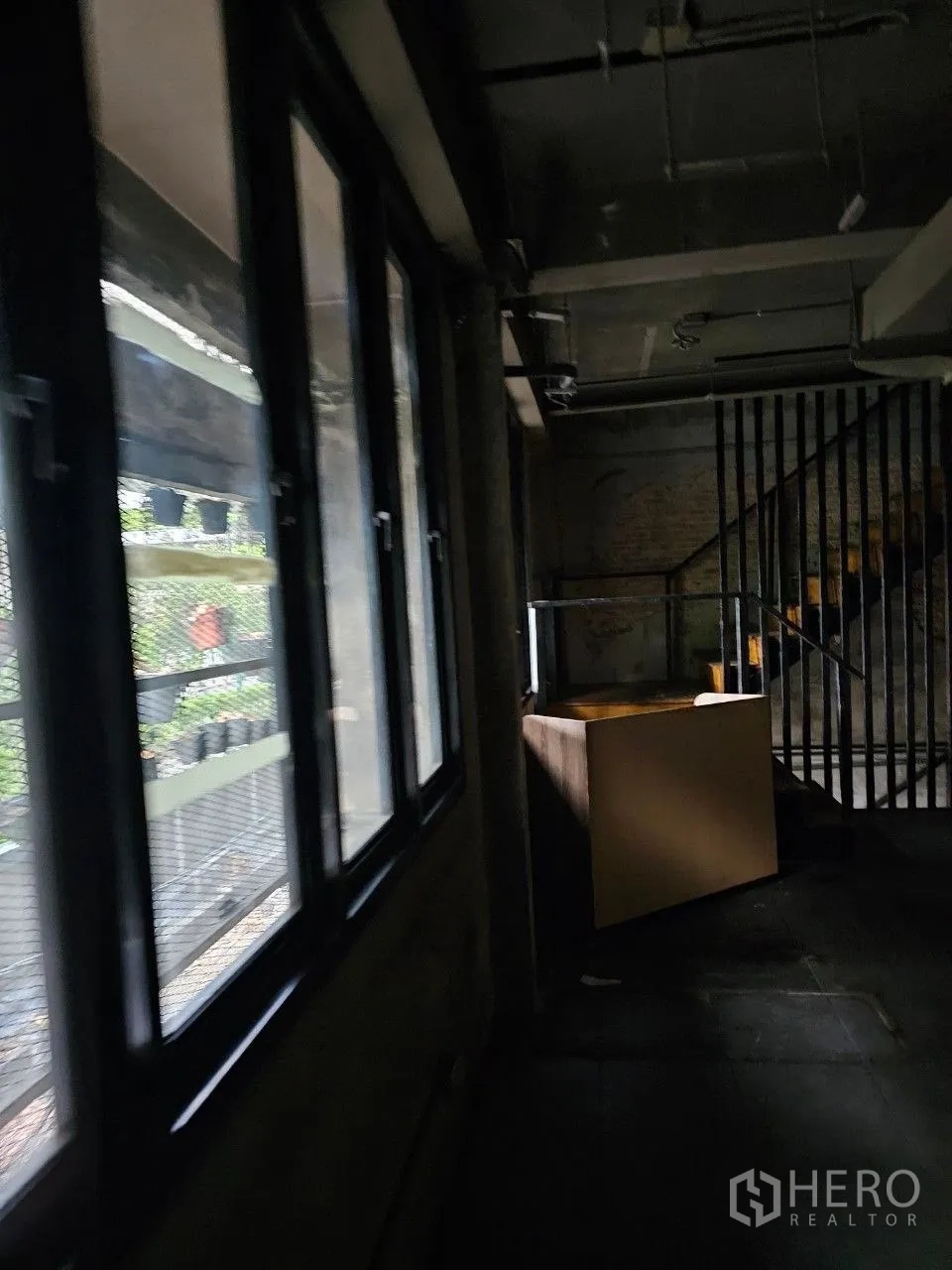 Shophouse for rent or sale in Watthana, Bangkok - Corridor lined with tall windows bringing natural light beside a staircase landing.