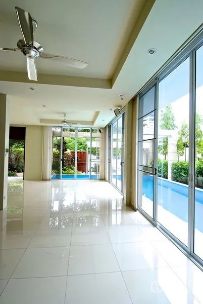 Detached House for rent in Watthana, Bangkok - Long bright hallway with ceiling fans and sliding glass opening to the poolside.