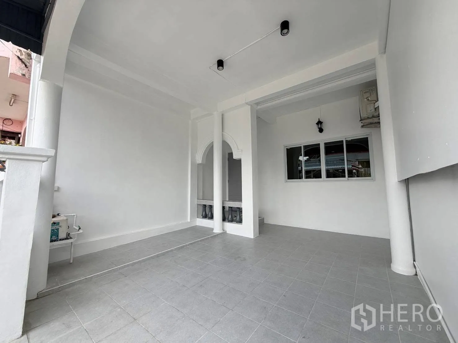 Townhouse for rent in Phra Khanong, Bangkok - Covered front carport or terrace with tiled floor, columns and a window.