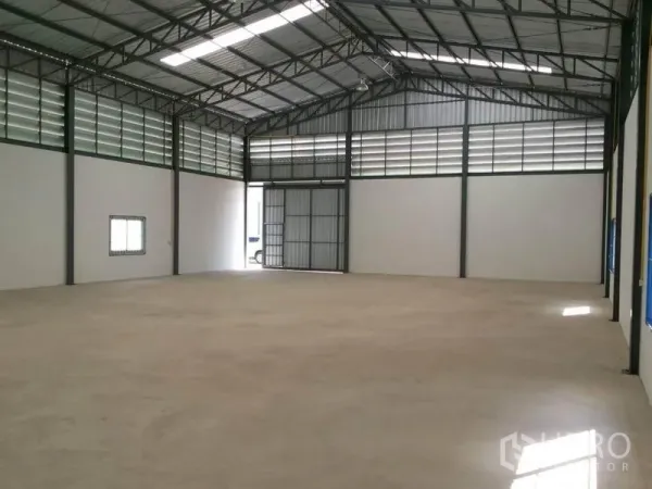 Warehouse for rent in Lam Luk Ka, Pathum Thani - Spacious 375 sqm warehouse interior with high steel truss roof, louvered vents, and a large sliding entry door.