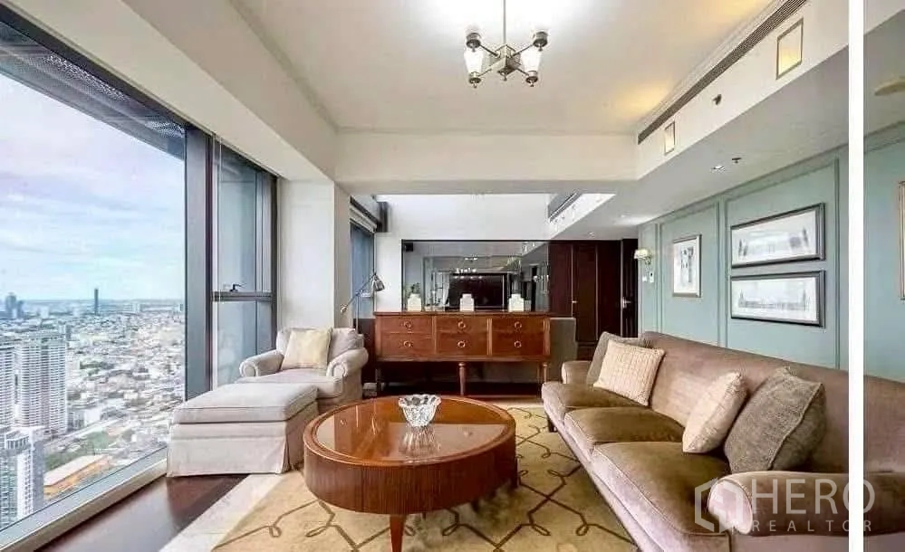 Condominium for rent in Sathon, Bangkok - Cozy sitting corner with sofa, armchair and sideboard framed by wide skyline windows.