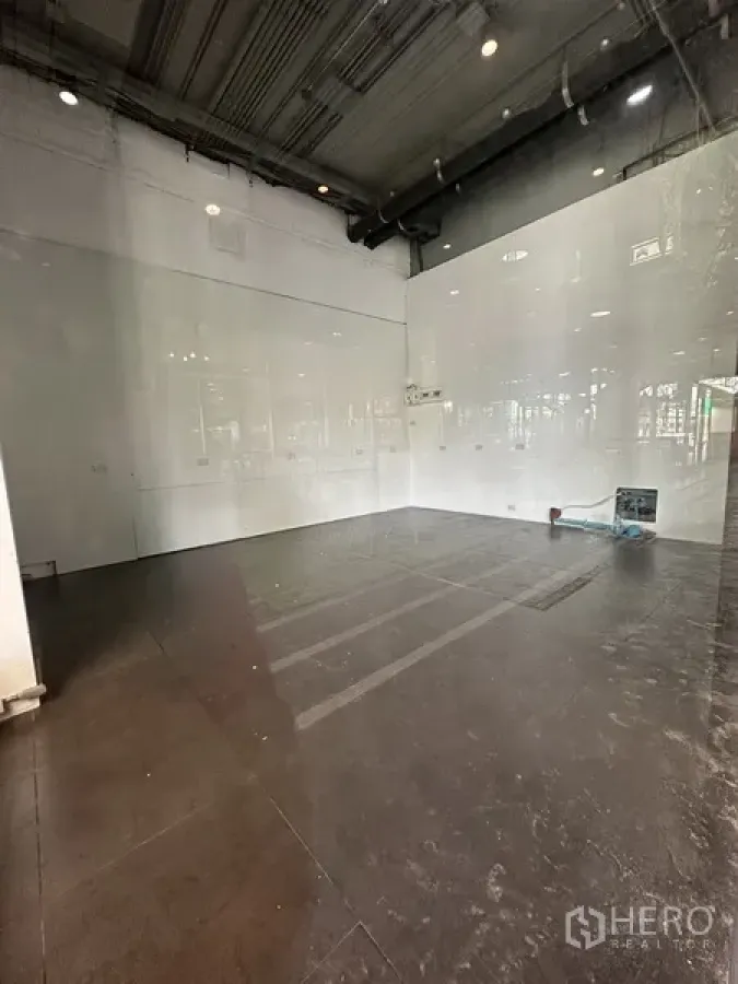Retail Space for rent in Khlong Toei, Bangkok - Empty 63 sq m retail interior with high exposed ceiling, white walls and dark tiled floor ready for fit-out.