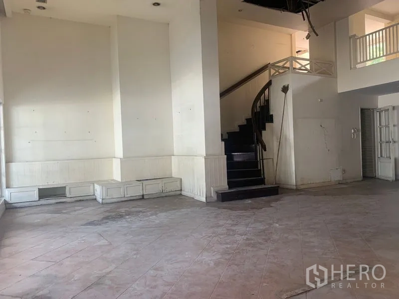 Shophouse for rent in Watthana, Bangkok - Double-height lobby space featuring a curved staircase and mezzanine.