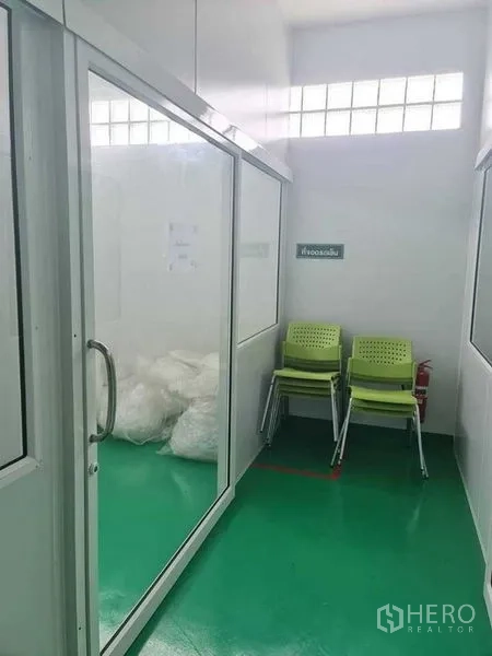 Factory for sale in Bang Pa-in, Phra Nakhon Si Ayutthaya - Small glass room with stacked chairs and bagged materials.