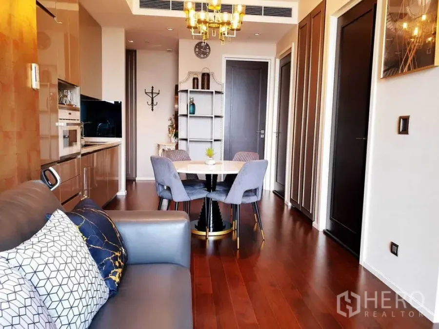 Condominium for rent or sale in Watthana, Bangkok - Dining nook with round table and grey chairs beside a glossy kitchen and wood floors.