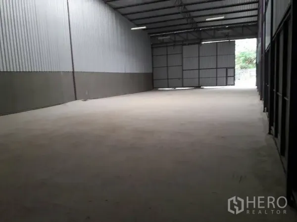 Warehouse for rent in Lam Luk Ka, Pathum Thani - Open-plan warehouse space with wide sliding doors and ample loading area at the entrance.