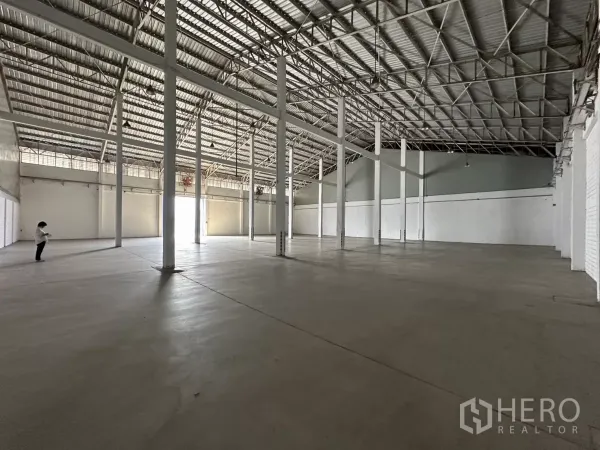 Warehouse for rent in Phra Khanong, Bangkok - Angle view of large clear-span warehouse hall with tall columns and metal roof, ample open floor space.