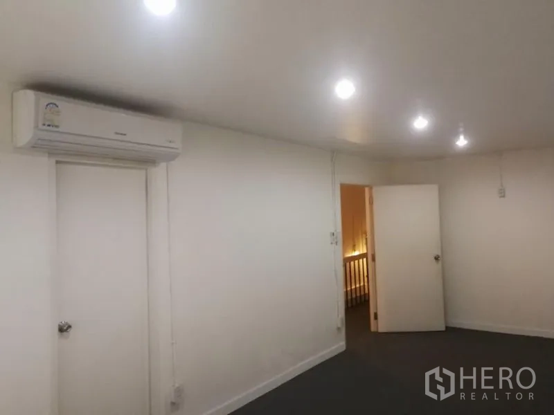 Townhouse for rent in Khlong Toei, Bangkok - Upper-floor room with recessed ceiling lights, air conditioner and doorway