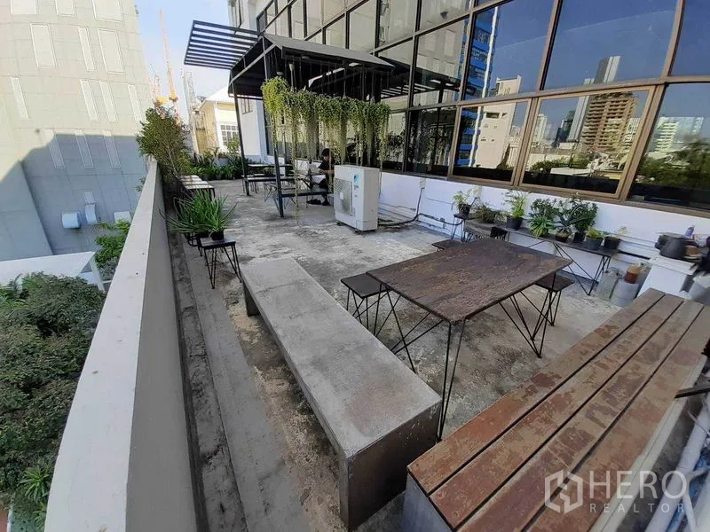 Office Space for rent in Khlong Toei, Bangkok - Outdoor terrace with benches, tables, potted plants and city views beside a glass façade.