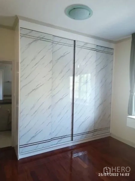 Detached House for sale in Prawet, Bangkok - Bedroom with marble-look sliding wardrobe and polished wood floors.
