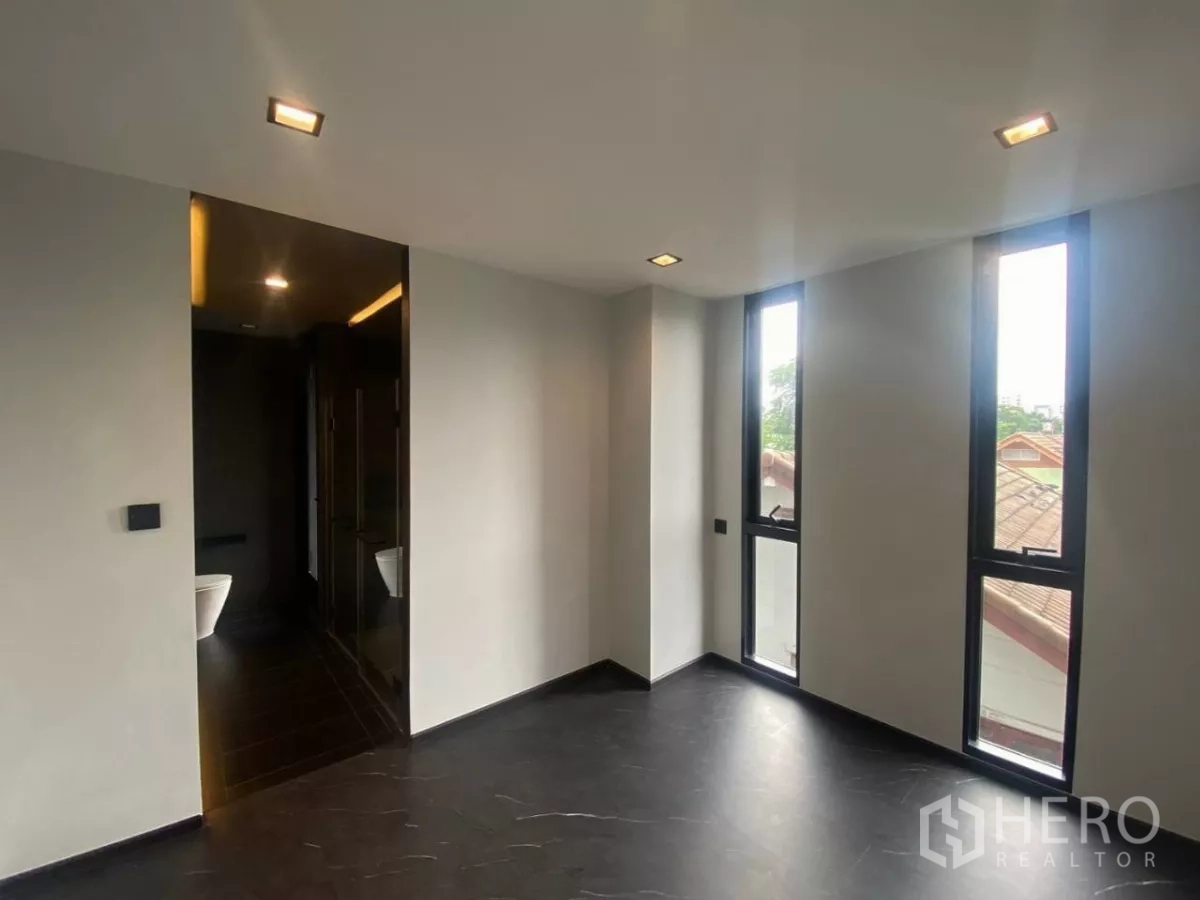 Townhouse for rent in Huai Khwang, Bangkok - Bedroom with ensuite entrance and three tall narrow windows.