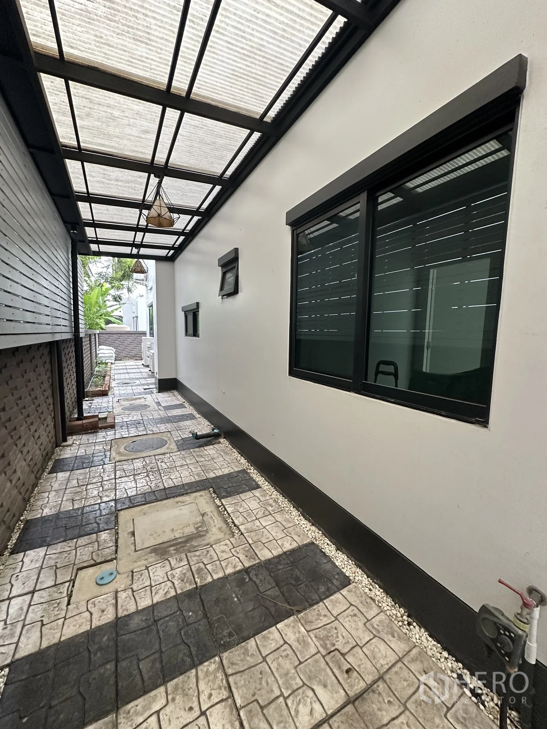 Detached House for rent in Lam Luk Ka, Pathum Thani - Covered side walkway with translucent roof and paver path.