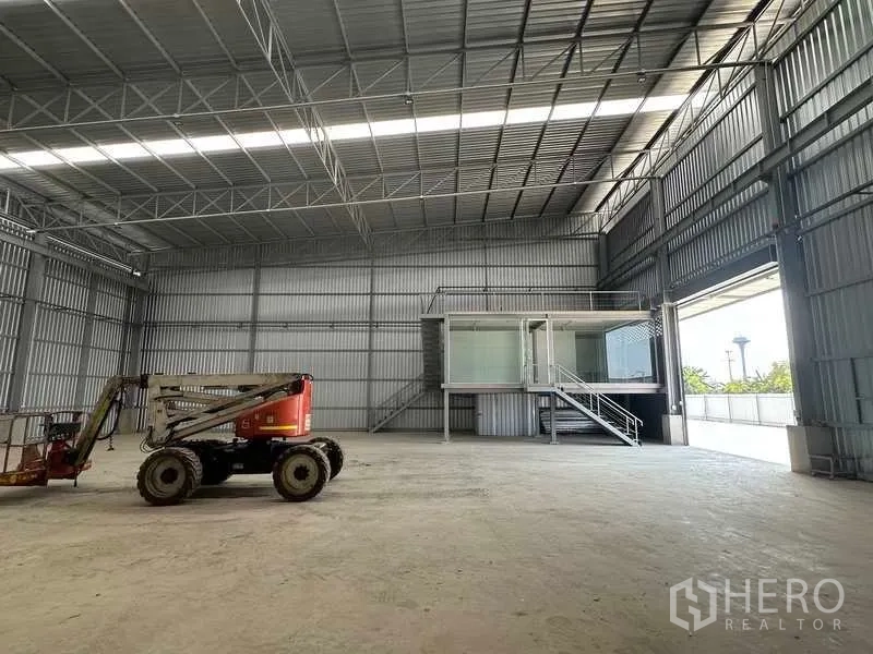 Factory for rent in Wang Noi, Phra Nakhon Si Ayutthaya - Open warehouse bay showing the mezzanine glass office and a large shutter door leading to the yard.