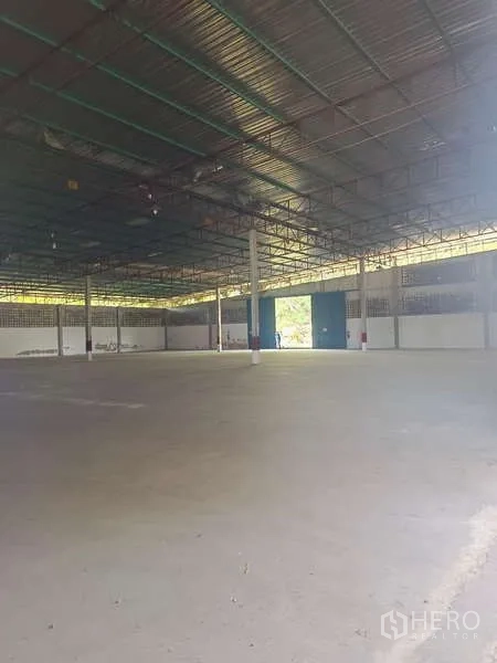 Warehouse for rent in Mueang Rayong, Rayong - Expansive warehouse floor with steel truss roof and daylight entering from a large doorway.