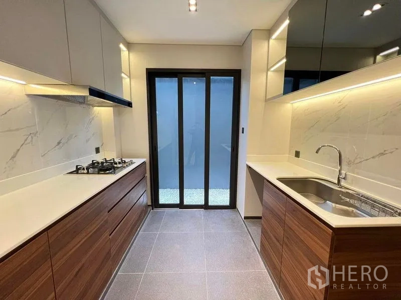 Detached House for sale in Suan Luang, Bangkok - Enclosed Thai kitchen with gas stove, stone countertops and under-cabinet lighting.