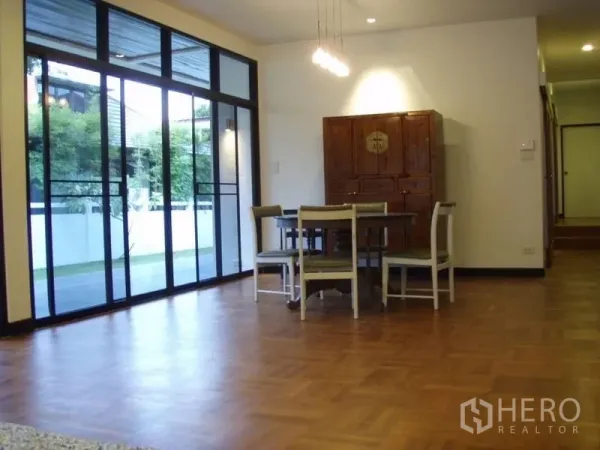 Detached House for rent in Huai Khwang, Bangkok - Open dining area with parquet flooring, pendant lights and floor-to-ceiling glass doors to garden