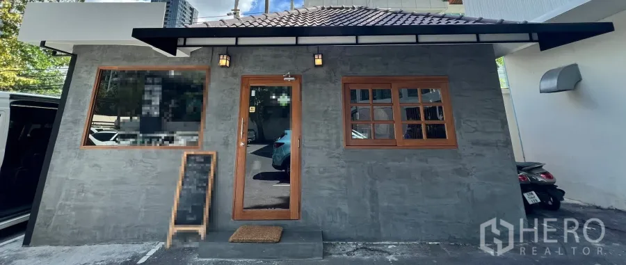 Retail Space for rent in Watthana, Bangkok - Renovated single-storey retail space with gray facade, wood-framed door and windows, canopy, and parking in Watthana, Bangkok.