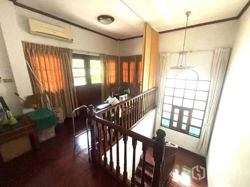 Detached House for sale in Suan Luang, Bangkok - Upper landing with wooden staircase, large arched window and chandelier.