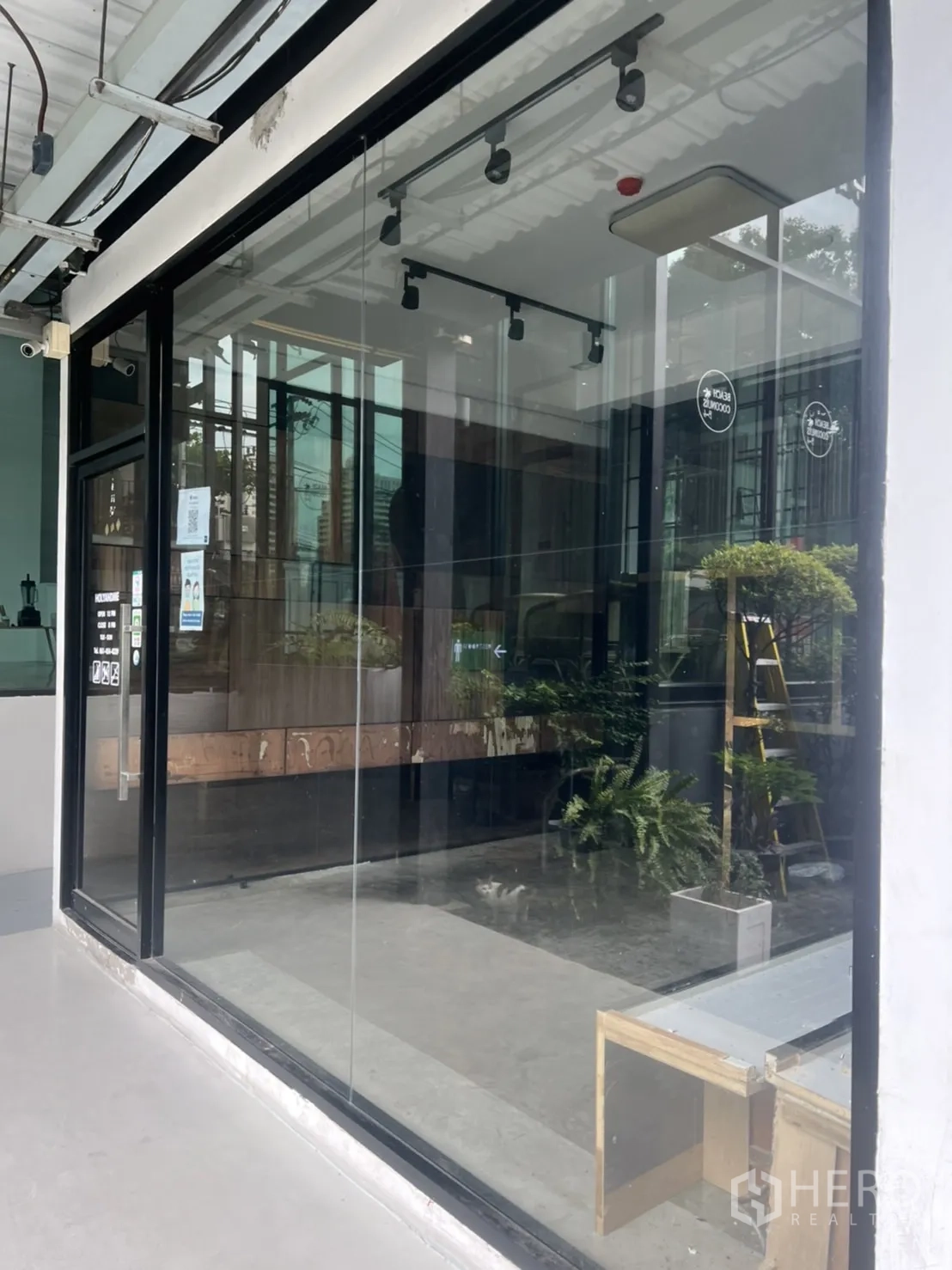 Retail Space for rent in Watthana, Bangkok - Street-level retail unit with full-height glass frontage, black metal frame, track lighting and concrete floor inside.