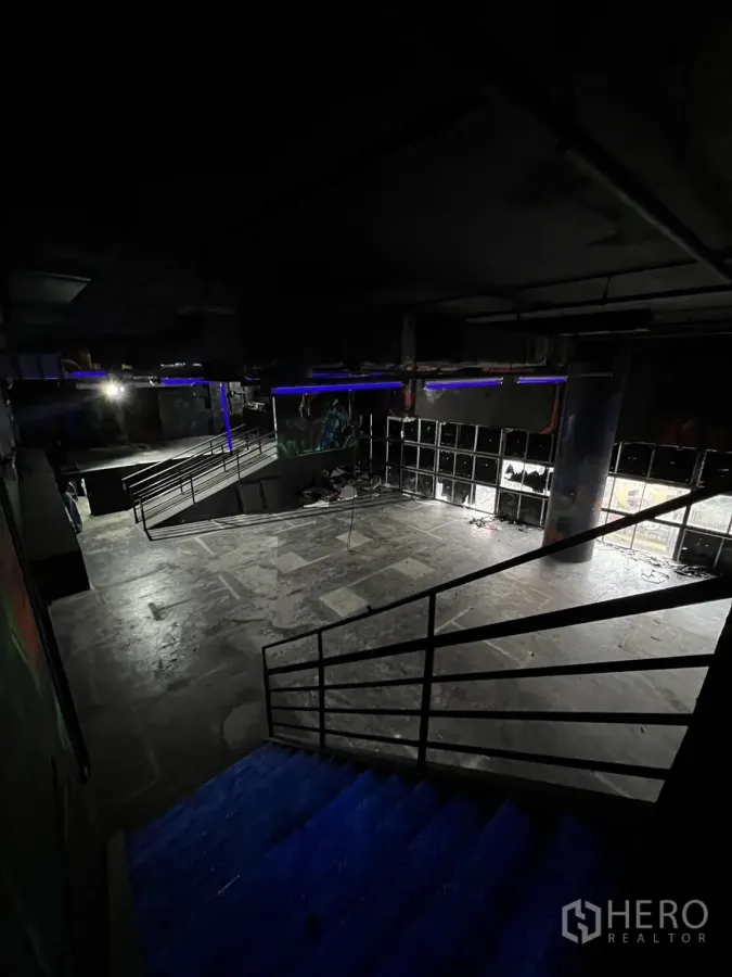 Retail Space for rent in Khlong Toei, Bangkok - Staircase with metal railings leading to a large open concrete floor in a dim interior.