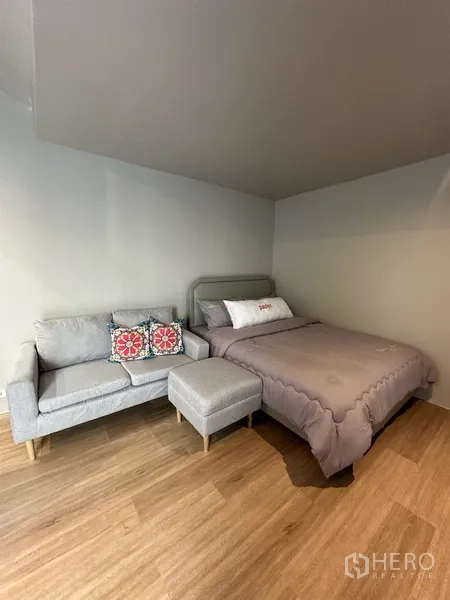 Home Office for rent in Suan Luang, Bangkok - Compact studio space with bed, sofa and wood-style flooring.