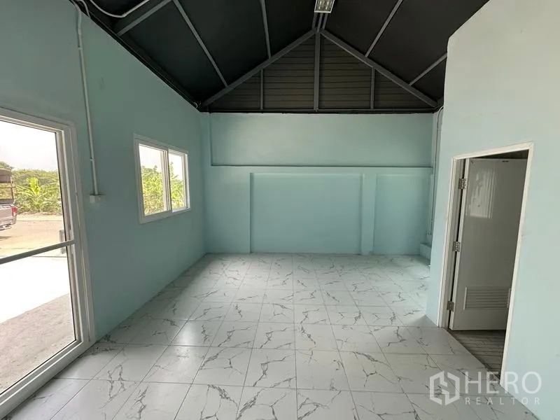 Factory for rent in Pak Kret, Nonthaburi - Bright office interior with marble-look tiled flooring, windows and an adjacent restroom door.