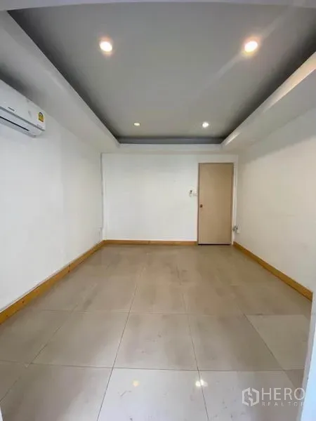 Townhouse for rent in Khlong Toei, Bangkok - Bright empty room with recessed lighting, tiled floor, and wall-mounted air conditioner.