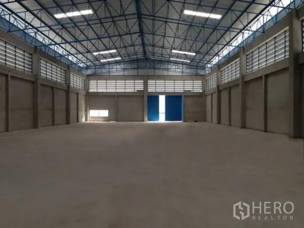 Warehouse for rent in Mueang Samut Prakan, Samut Prakan - Spacious warehouse interior with high steel truss roof, clerestory vents and wide blue sliding doors.