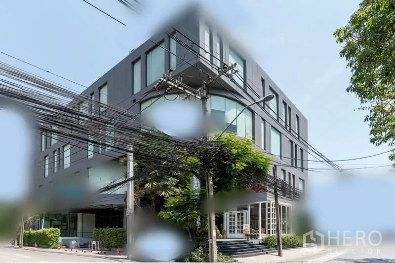 Retail Space for rent in Watthana, Bangkok - Exterior of a modern multi-storey commercial building with large windows and greenery in Watthana, Bangkok.