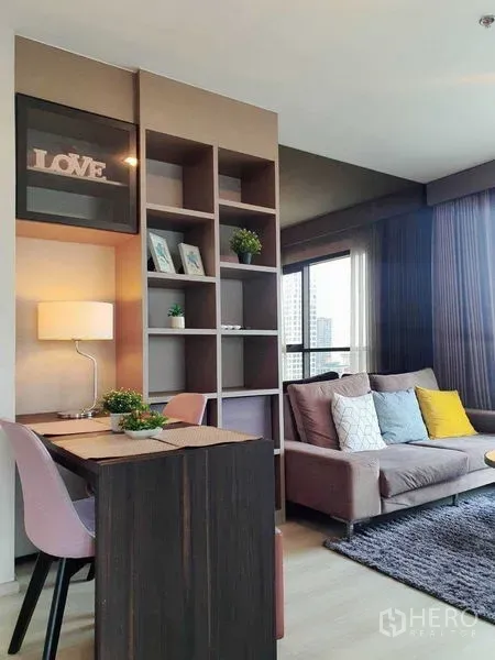 Condominium for sale in Khlong Toei, Bangkok - Bright living area with built‑in shelves, work desk, and sofa beside floor‑to‑ceiling windows at Life Sukhumvit 48.
