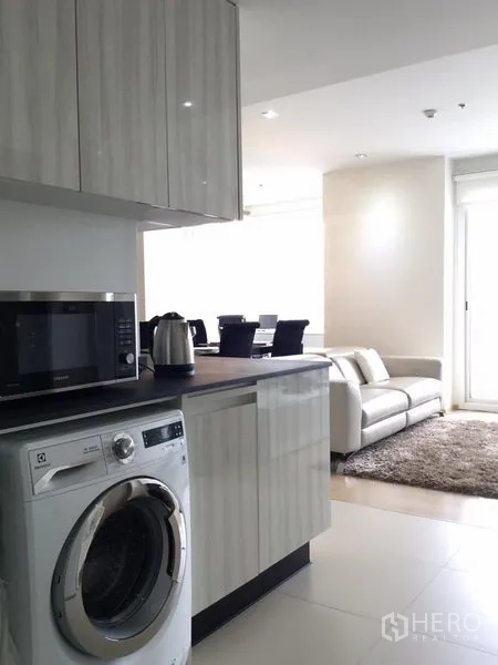 Condominium for rent or sale in Watthana, Bangkok - Modern kitchen with glossy cabinets, countertop appliances and a front-loading washer.