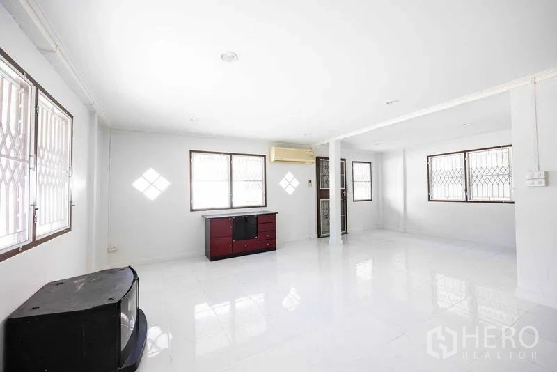 Home Office for rent in Watthana, Bangkok - Large open living or work space with multiple windows and security grilles allowing natural light.