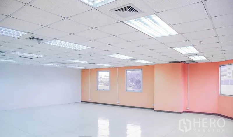 Office Space for rent in Bang Na, Bangkok - Corner office space with orange accent walls, windows, and ceiling air vents.