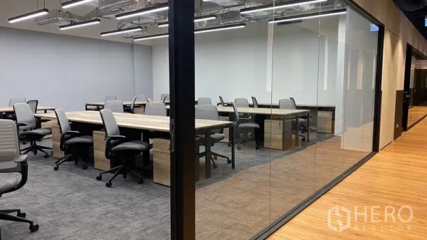 Office Space for rent in Pathum Wan, Bangkok - Glass-partitioned office area with shared desks, carpeted floor, exposed ceiling ducts and a wood-floor corridor.