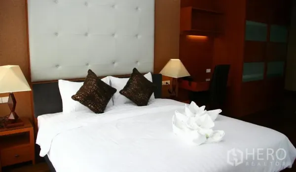 房间 出租在Khlong Toei, Bangkok - 卧室配白色软包床头、台灯与特大床