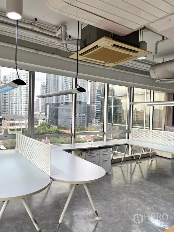 Office Space for rent in Khlong Toei, Bangkok - White shared desks with divider screens beside floor-to-ceiling glass and skyline outlook.