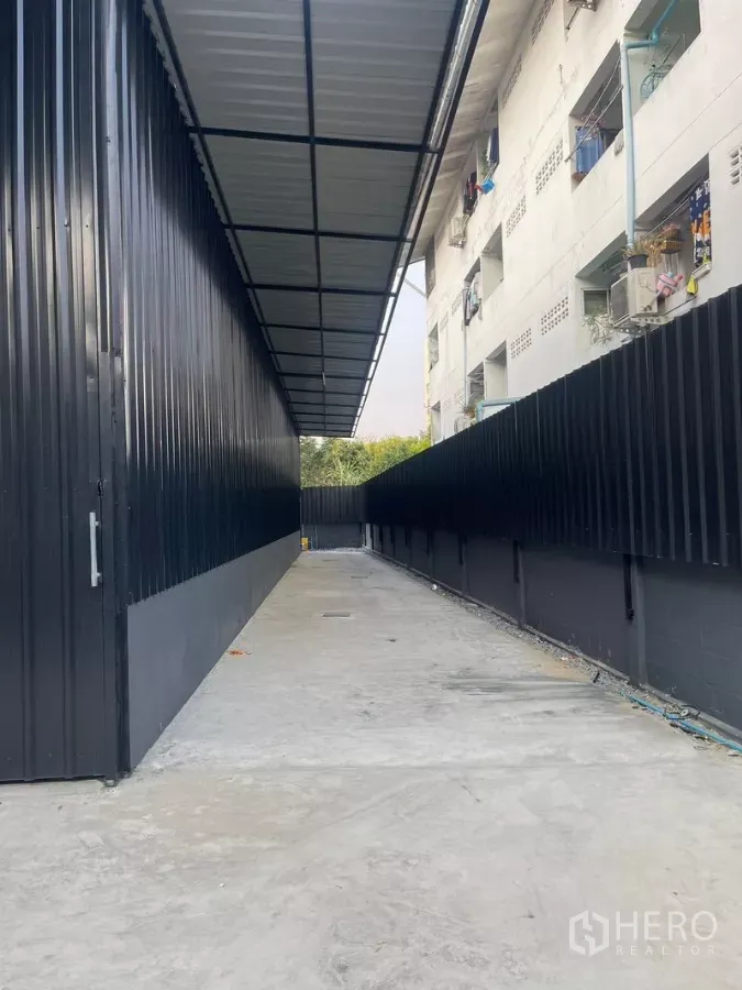 货栈 出租在Wang Thonglang, Bangkok - 仓库旁带顶棚的混凝土通道，黑色金属围墙保障出入安全。