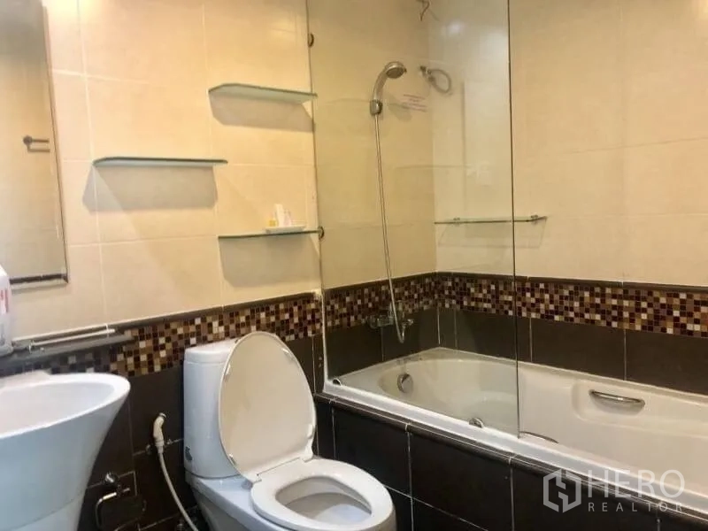 Condominium for rent in Khlong Toei, Bangkok - Bathroom with bathtub-shower combo, glass partition and mosaic accent tiles.