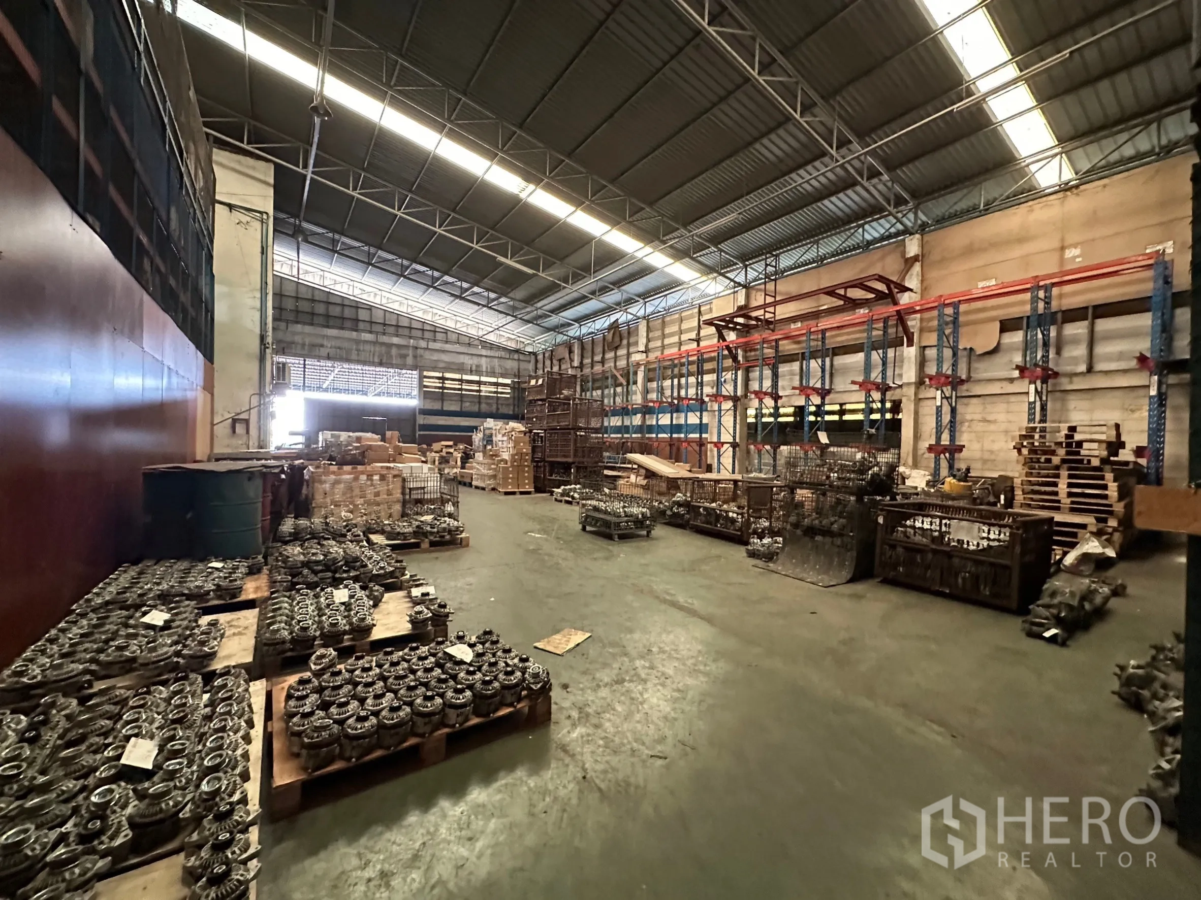 Factory for rent in Lam Luk Ka, Pathum Thani - Spacious factory warehouse with high steel roof, pallets and storage racks along a central aisle.