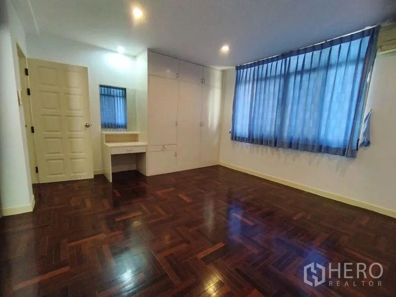 Detached House for rent in Watthana, Bangkok - Bedroom with parquet flooring, built-in wardrobe, and dressing table.