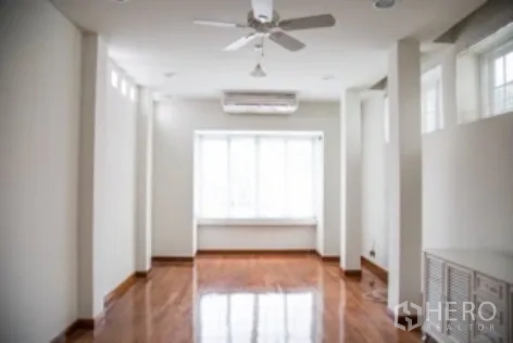 独立式住宅 出租在Khlong Toei, Bangkok - 狭长客厅，吊扇、木地板与大面积窗台座位。