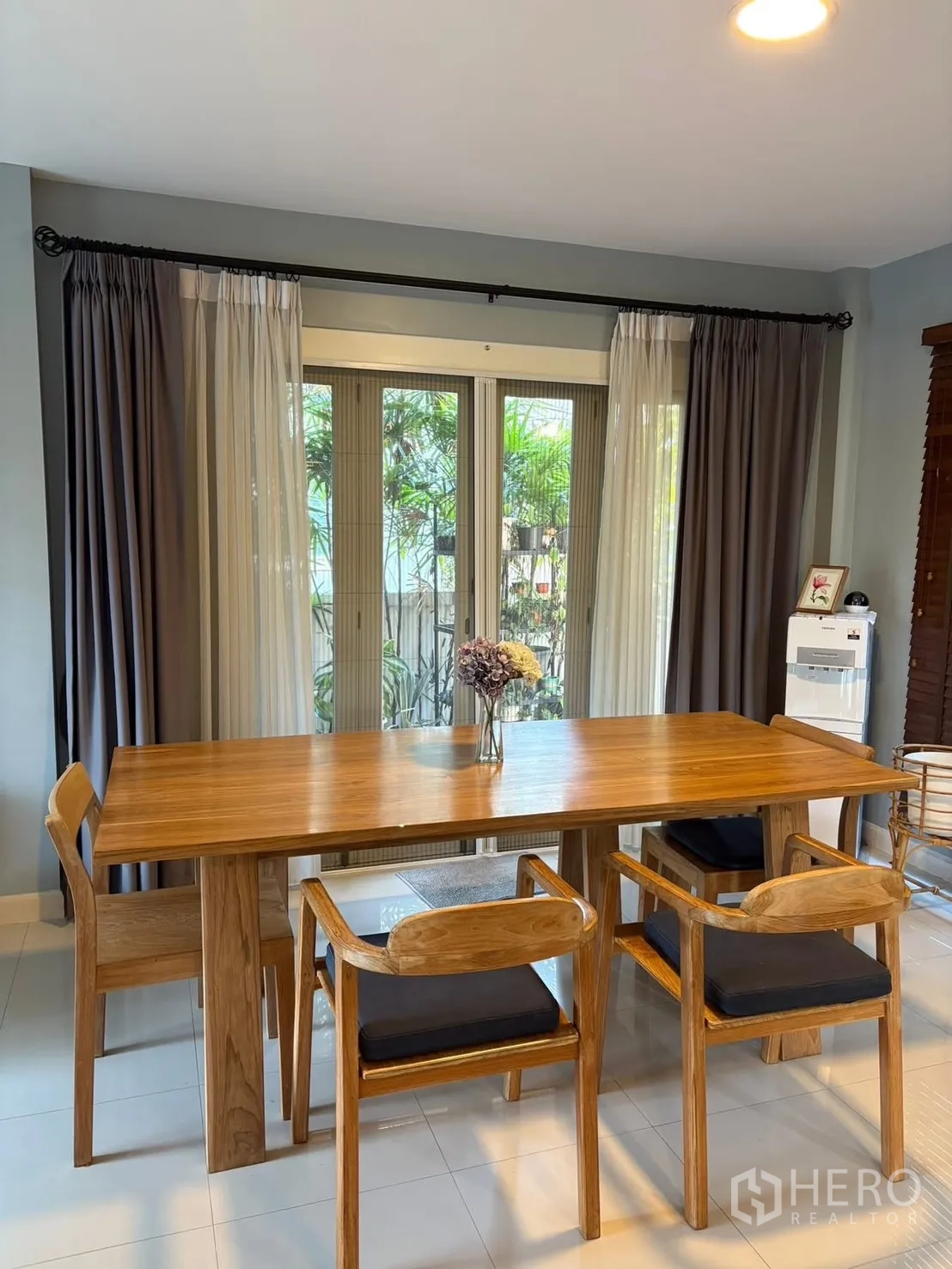 Detached House for rent in Prawet, Bangkok - Dining area with wooden table and chairs beside sliding glass doors.