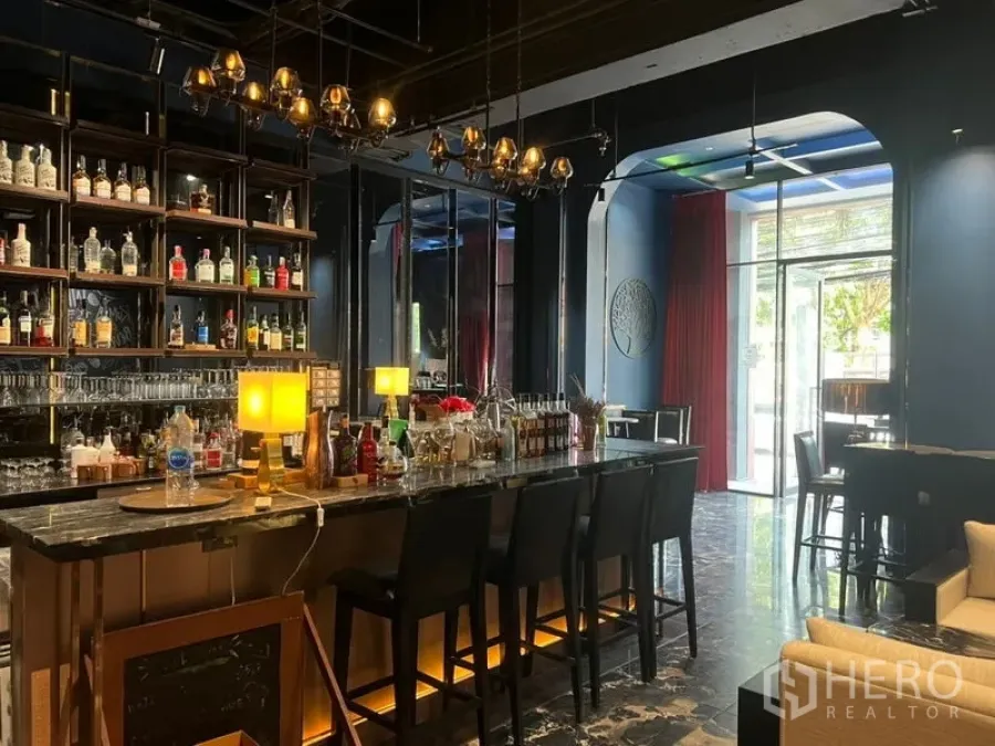 Retail Space for rent in Watthana, Bangkok - Stylish retail space featuring a marble bar counter, illuminated back shelving, pendant chandelier lighting, and high stools beside a street‑facing glass entry.