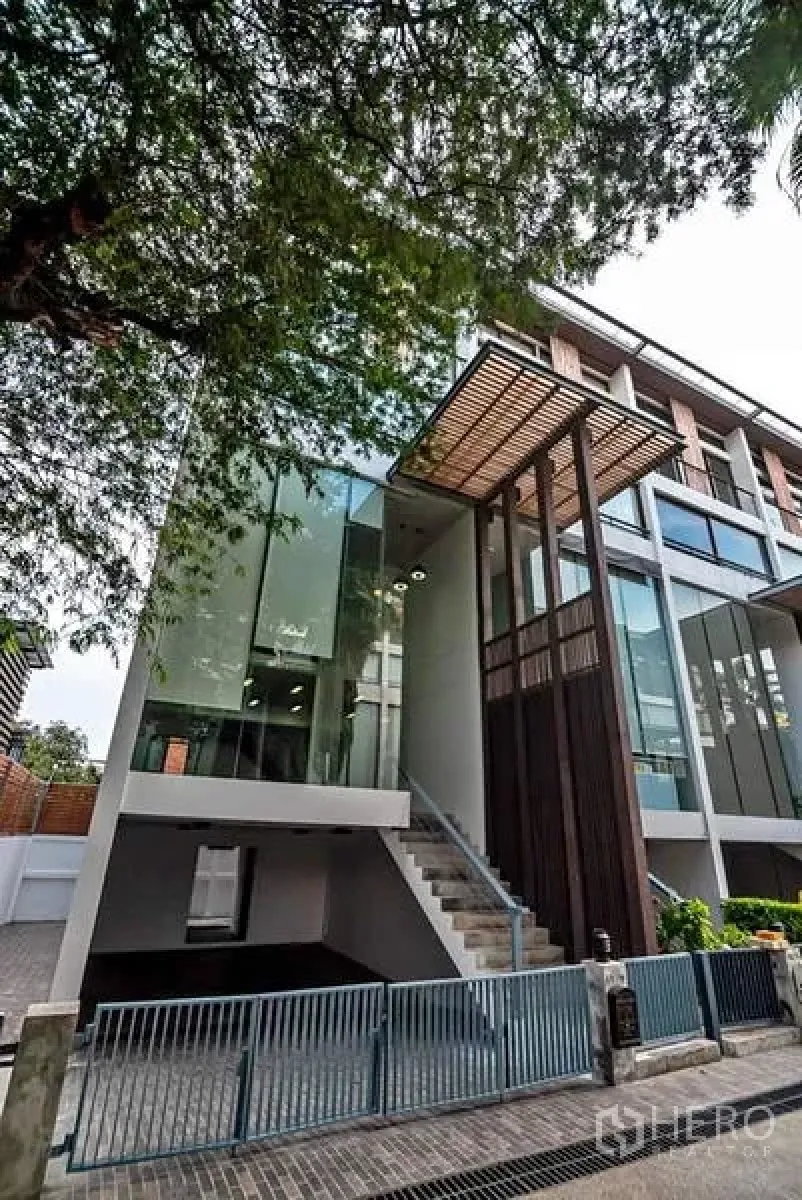 Townhouse for rent or sale in Phra Khanong, Bangkok - Modern multi-storey townhouse in Phra Khanong with glass facade, timber screen and gated driveway near BTS Punnawithi.