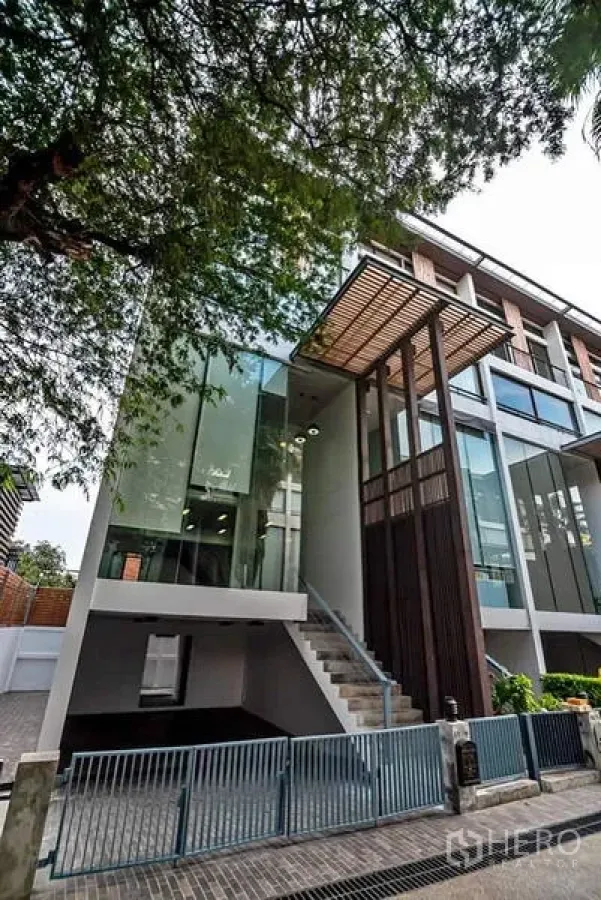 Townhouse for rent or sale in Phra Khanong, Bangkok - Modern multi-storey townhouse in Phra Khanong with glass facade, timber screen and gated driveway near BTS Punnawithi.