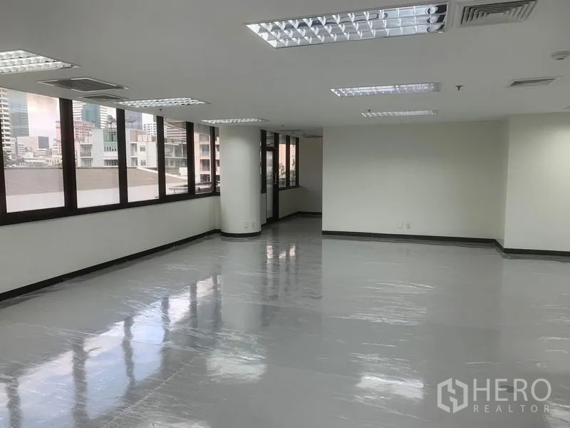 Office Space for rent in Bang Rak, Bangkok - Bright side wing of the office with multiple windows, ceiling lights, and urban views.