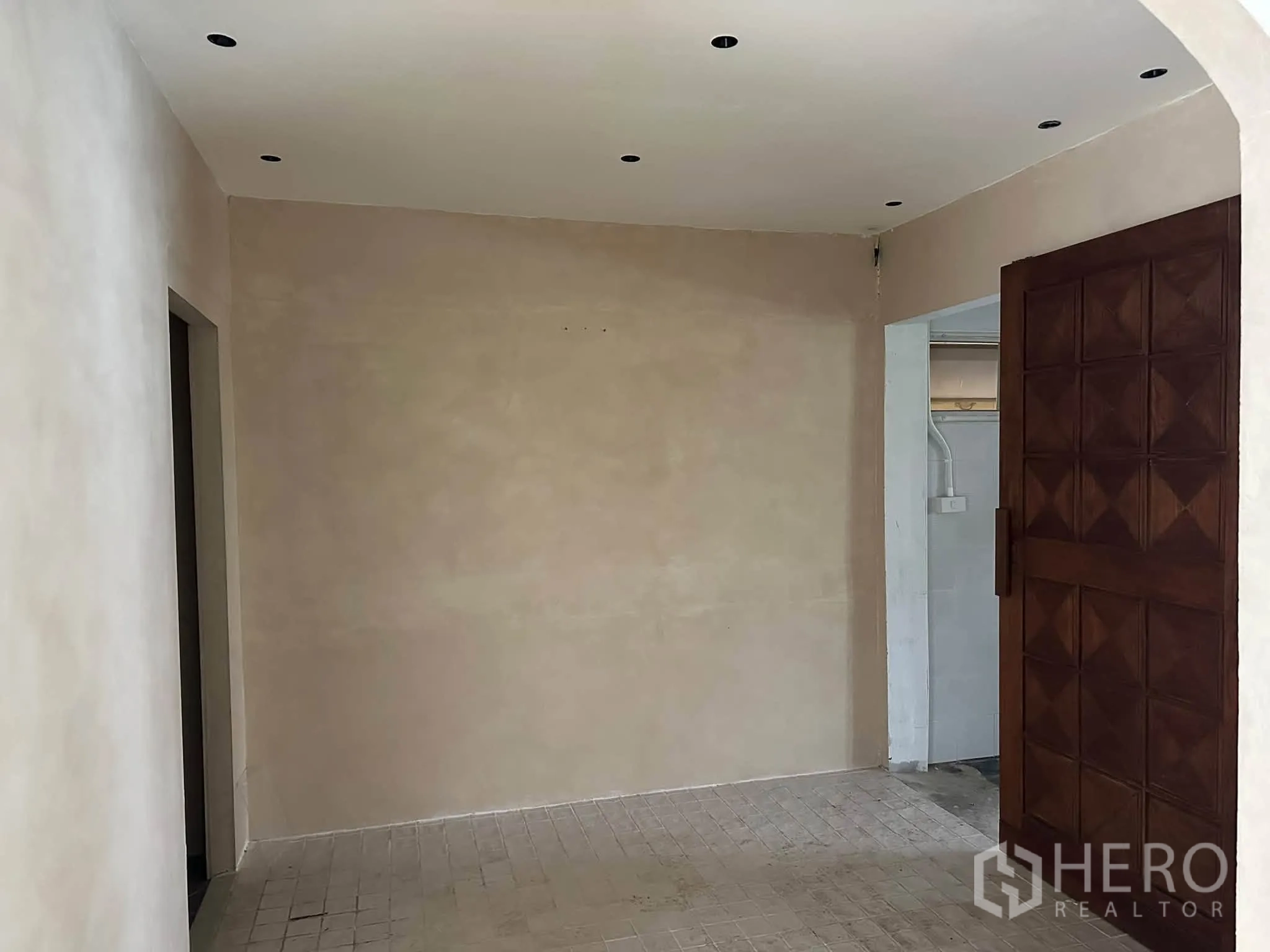 Retail Space for rent in Khlong Toei, Bangkok - Small foyer with textured walls and a large patterned wooden door.