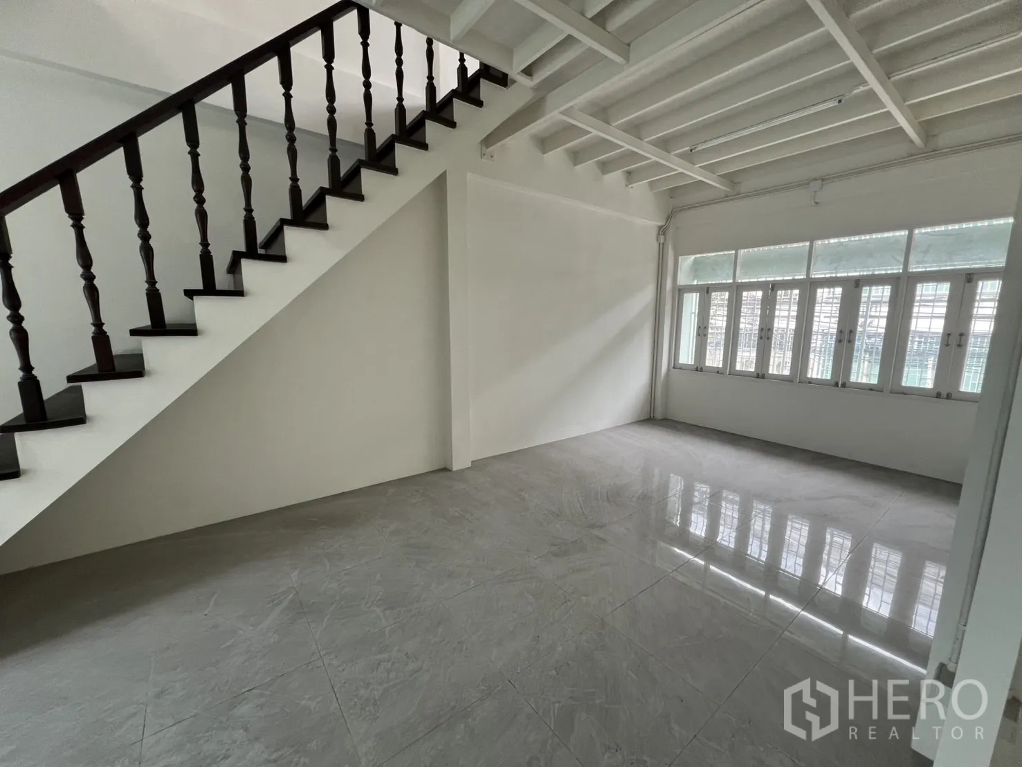 Shophouse for rent in Khlong Toei, Bangkok - Upper-level room with dark wood staircase and large windows.
