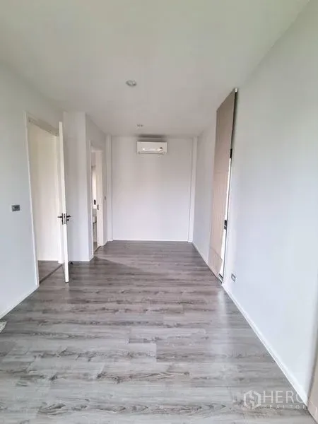 Detached House for rent - Bright upper-floor room with grey wood floors, white walls, split air conditioner and doorway in a modern detached house.